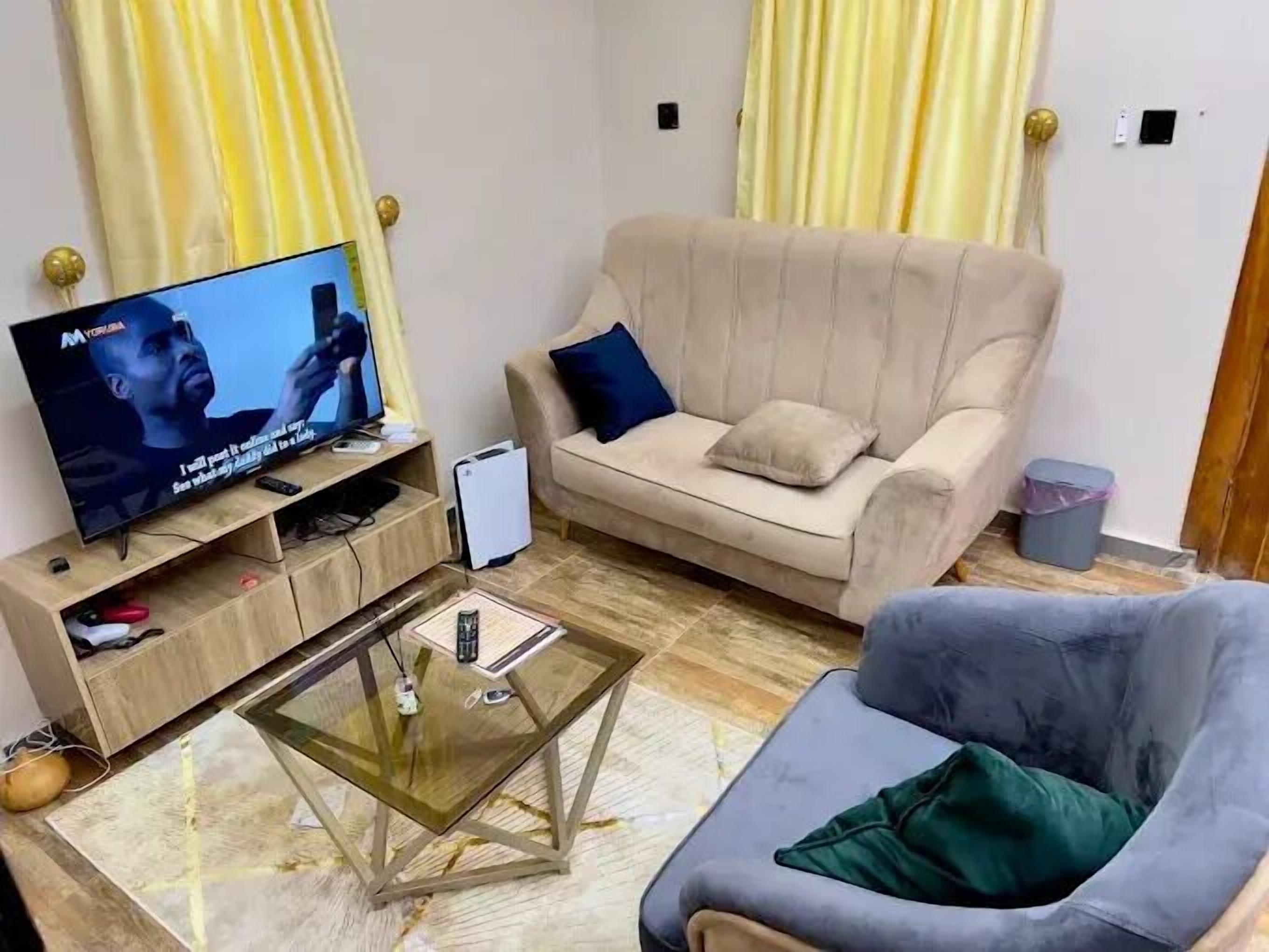 Un saló amb televisió, un sofà, una taula de centre de vidre i un butàc gris.
