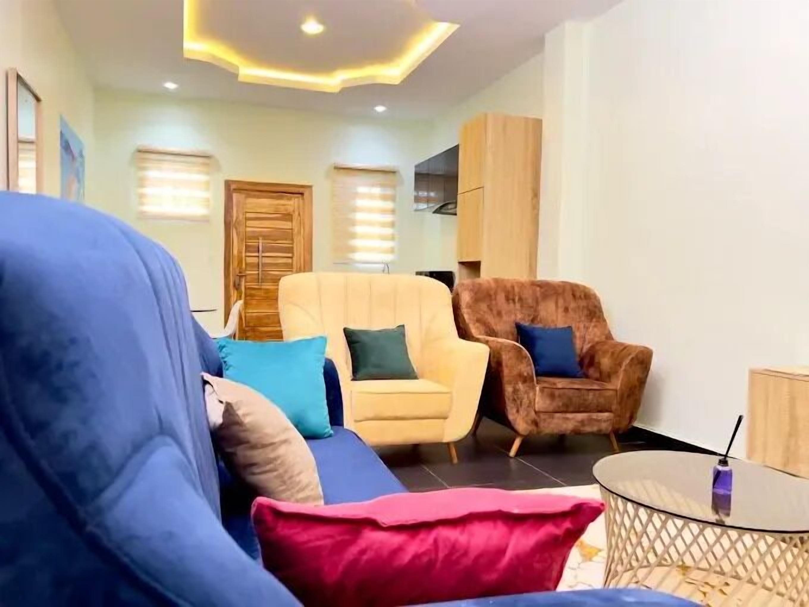 A modern living room with a blue sofa, a yellow armchair, and a brown armchair, each with matching cushions.
