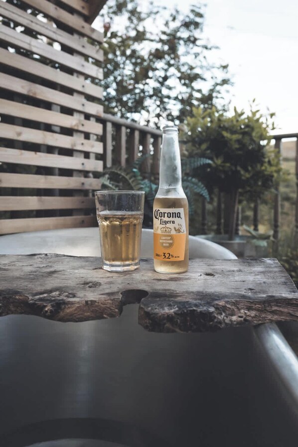 Una botella de cerveza Corona y un vaso sobre una mesa de madera al aire libre.