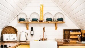 A kitchen with wooden cabinets, a white countertop, a sink, a toaster, and a hanging light fixture.