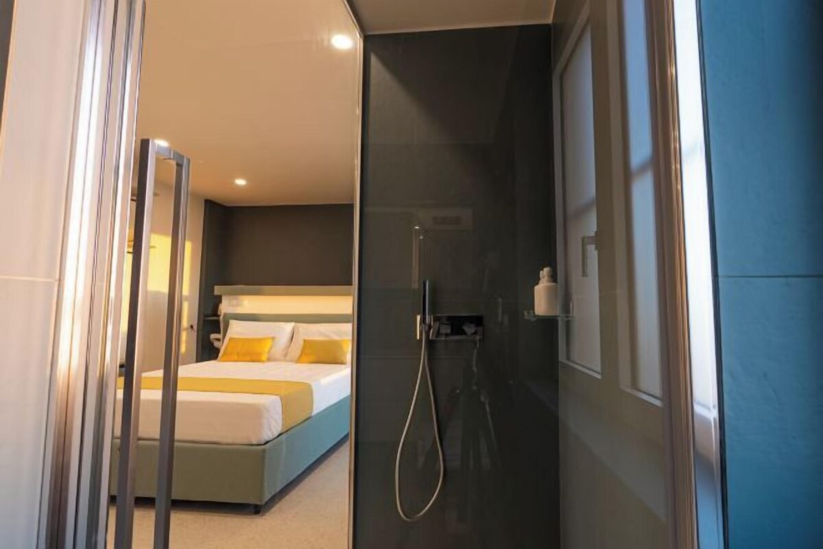Une chambre d’hôtel moderne équipée d’un lit, d’une douche et d’une paroi en verre.