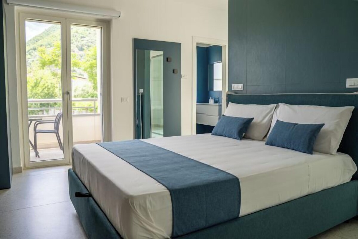A bedroom with a bed, a bathroom, and a balcony.