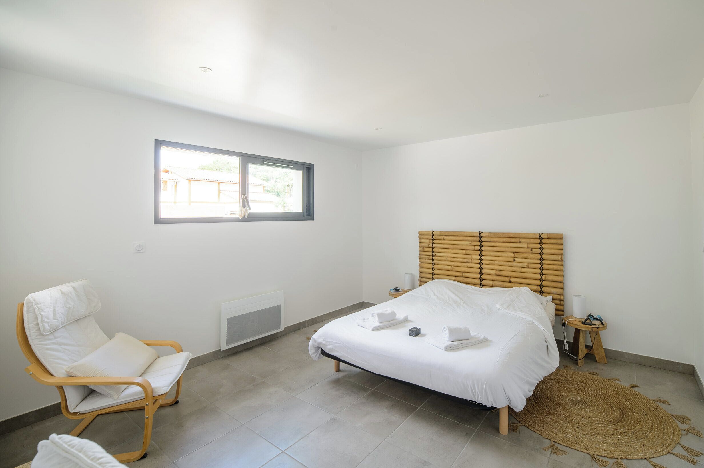 Ein Schlafzimmer mit einem Bett, einem Sessel, einem Fenster und einer Heizung.