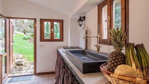 A kitchen with a large sink, wooden cabinets, and a view of a garden through an open door. - Passerina House: the unknown Umbria.  Old stone farmhouse with a view (Montegabbione)