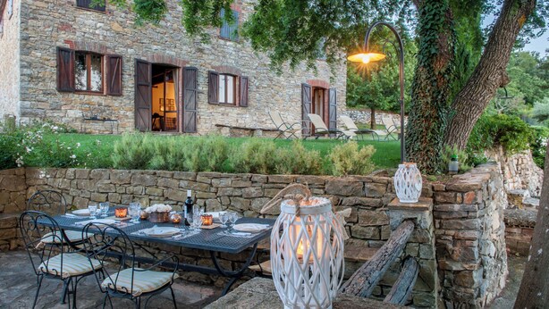 An outdoor dining area with stone walls, a table set for four, and a lantern. - Passerina House: the unknown Umbria.  Old stone farmhouse with a view (Montegabbione)