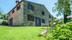 A stone house with multiple windows and a well-maintained lawn. - Passerina House: the unknown Umbria.  Old stone farmhouse with a view (Montegabbione)