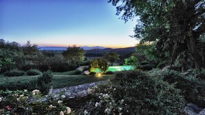 A landscaped garden with a stone pathway, various shrubs, and a well-lit tree. - Passerina House: the unknown Umbria.  Old stone farmhouse with a view (Montegabbione)