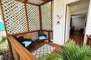 A covered outdoor seating area with wooden furniture and a lattice backdrop. - Large private property 2 mins to the Beach (West Bay)