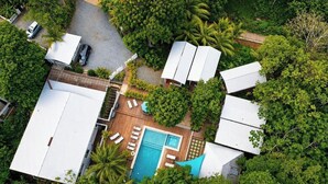 Vista aérea de una propiedad con piscina, varias edificaciones y abundante vegetación.