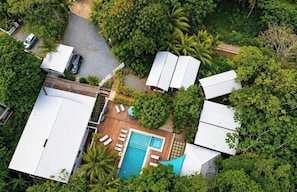 An aerial view of a property with a swimming pool, multiple buildings, and lush greenery. - Large private property 2 mins to the Beach (West Bay)