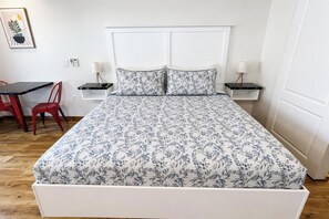 A bed with a floral bedspread, a white headboard, and two bedside tables with lamps.