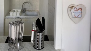 A compact kitchen with white cabinets, a sink, and a utensil holder. - Studio 26 m2 with pool & private parking (Juan-les-Pins)