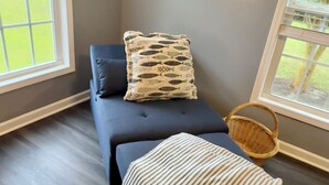 A massage therapy room with a dark-colored massage table, a striped blanket, and a patterned pillow.