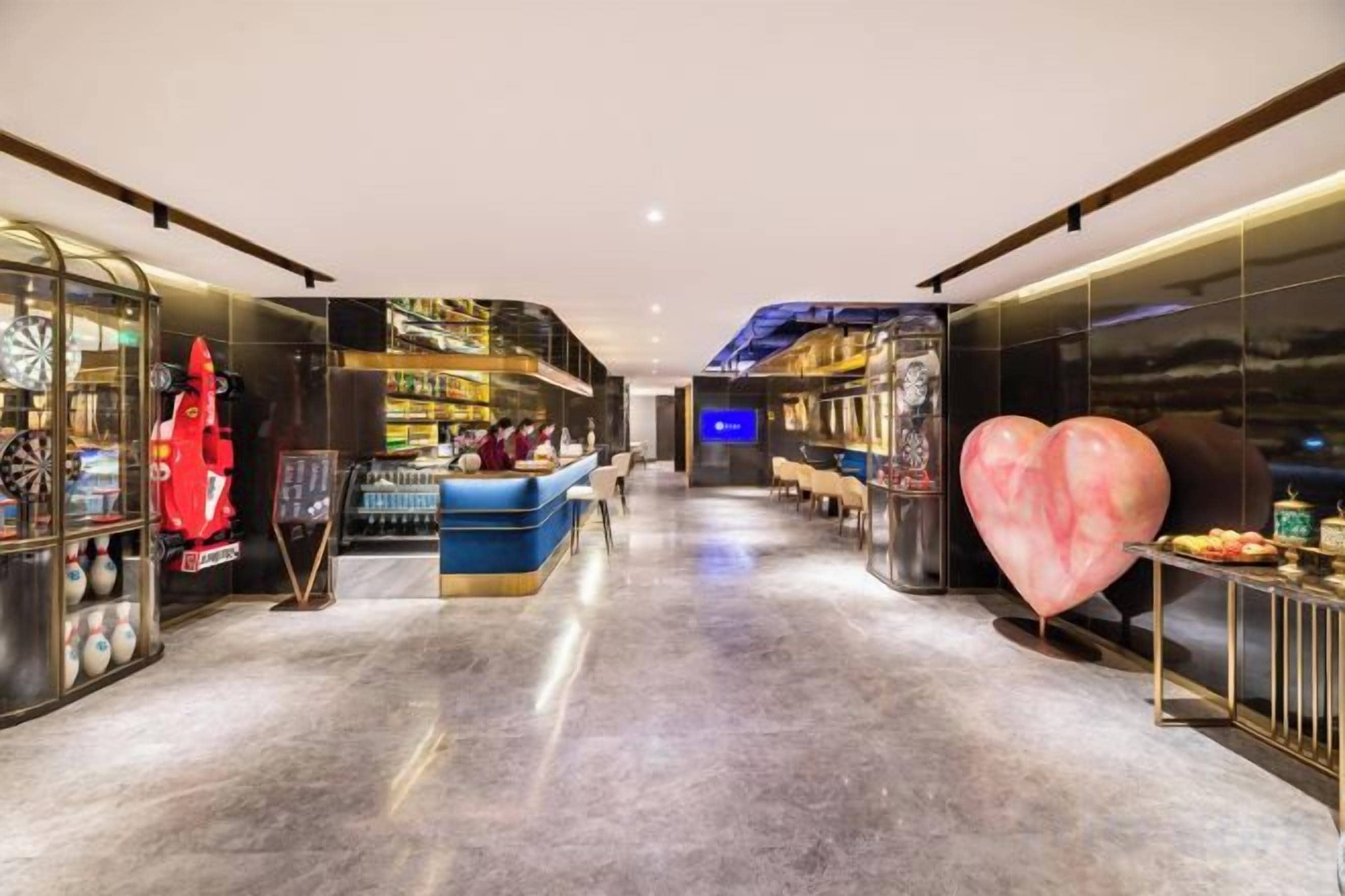 Een moderne hotellobby met een centraal zitgedeelte, een bar en een grote decoratie in de vorm van een hart.