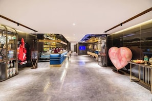 Un moderno vestíbulo de hotel con una zona de estar central, un bar y una gran decoración en forma de corazón.
