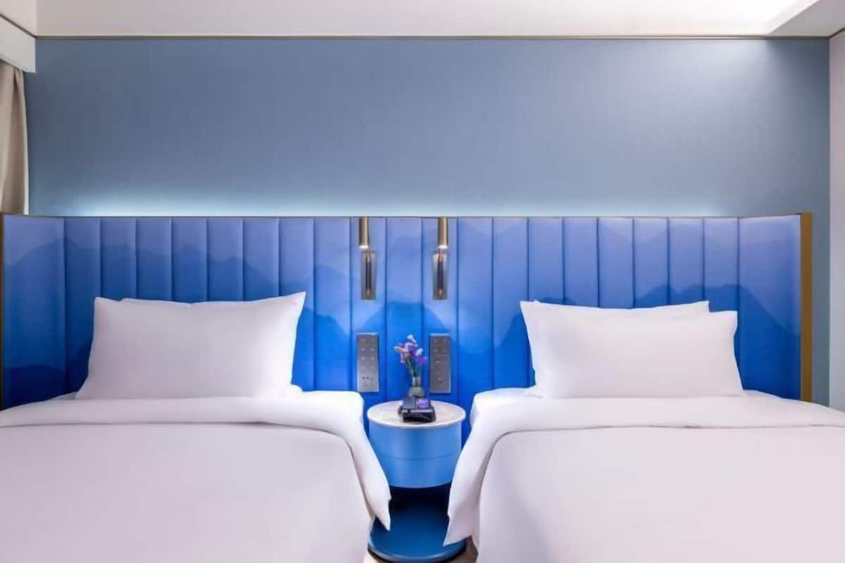 Una habitación de hotel con una cama grande, dos mesitas de noche y una pared decorada en azul.