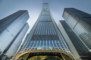 Un gratte-ciel moderne doté d’une façade en verre incurvée et d’une flèche centrale imposante.