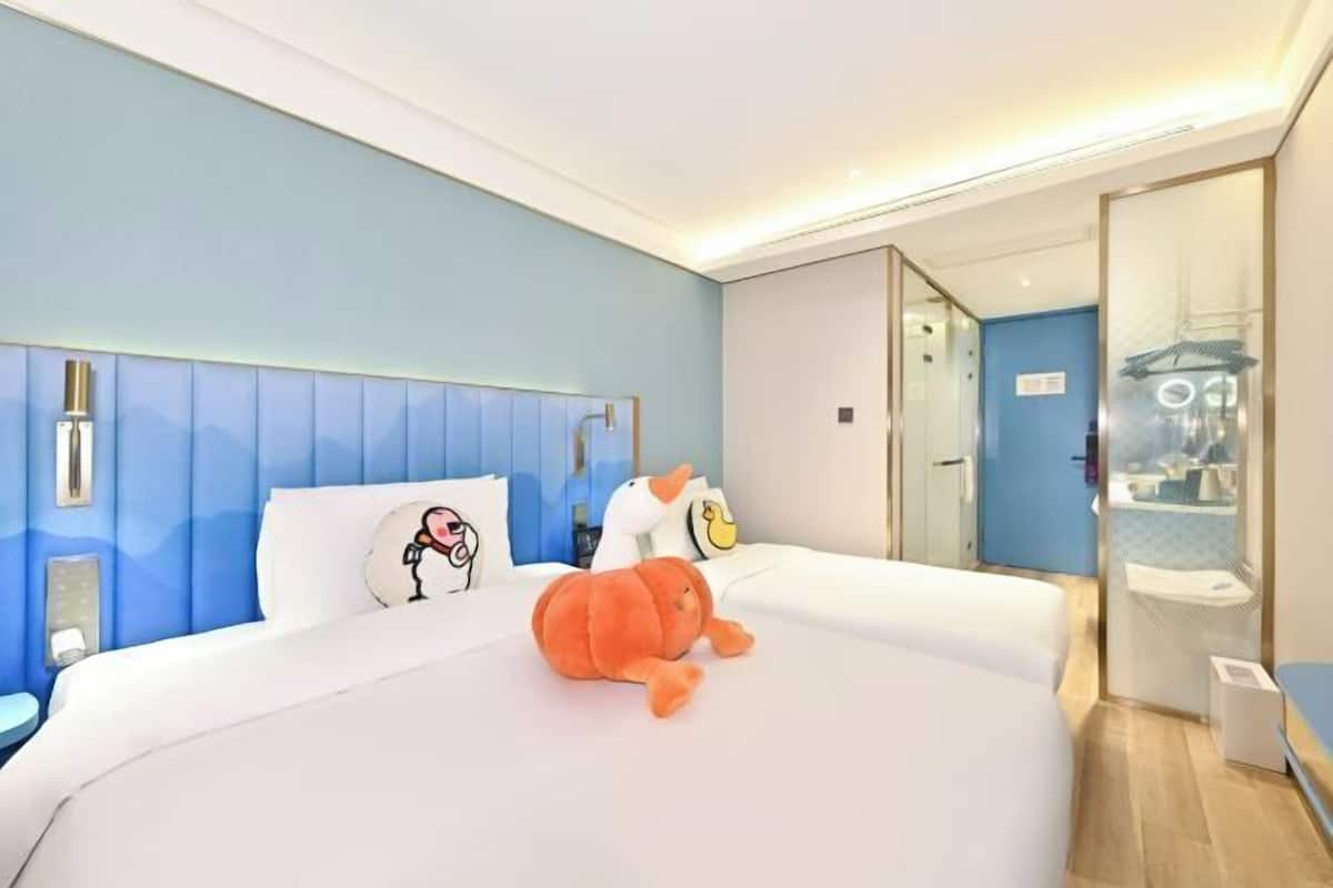 Una habitación de hotel con una cama, un peluche y un espejo.