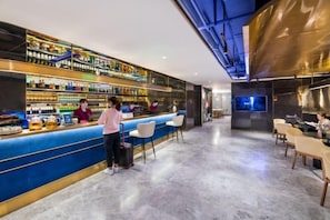 Un área de bar moderna con una barra azul, varias estanterías llenas de botellas y taburetes.