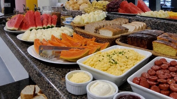 Un bufé con diversos alimentos, entre ellos frutas, pan y bollería.