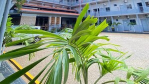 Un edificio de varios pisos con balcones, una zona de estacionamiento techada y un cielo despejado.