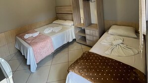 Habitación de hotel con dos camas, un armario y una mesita.