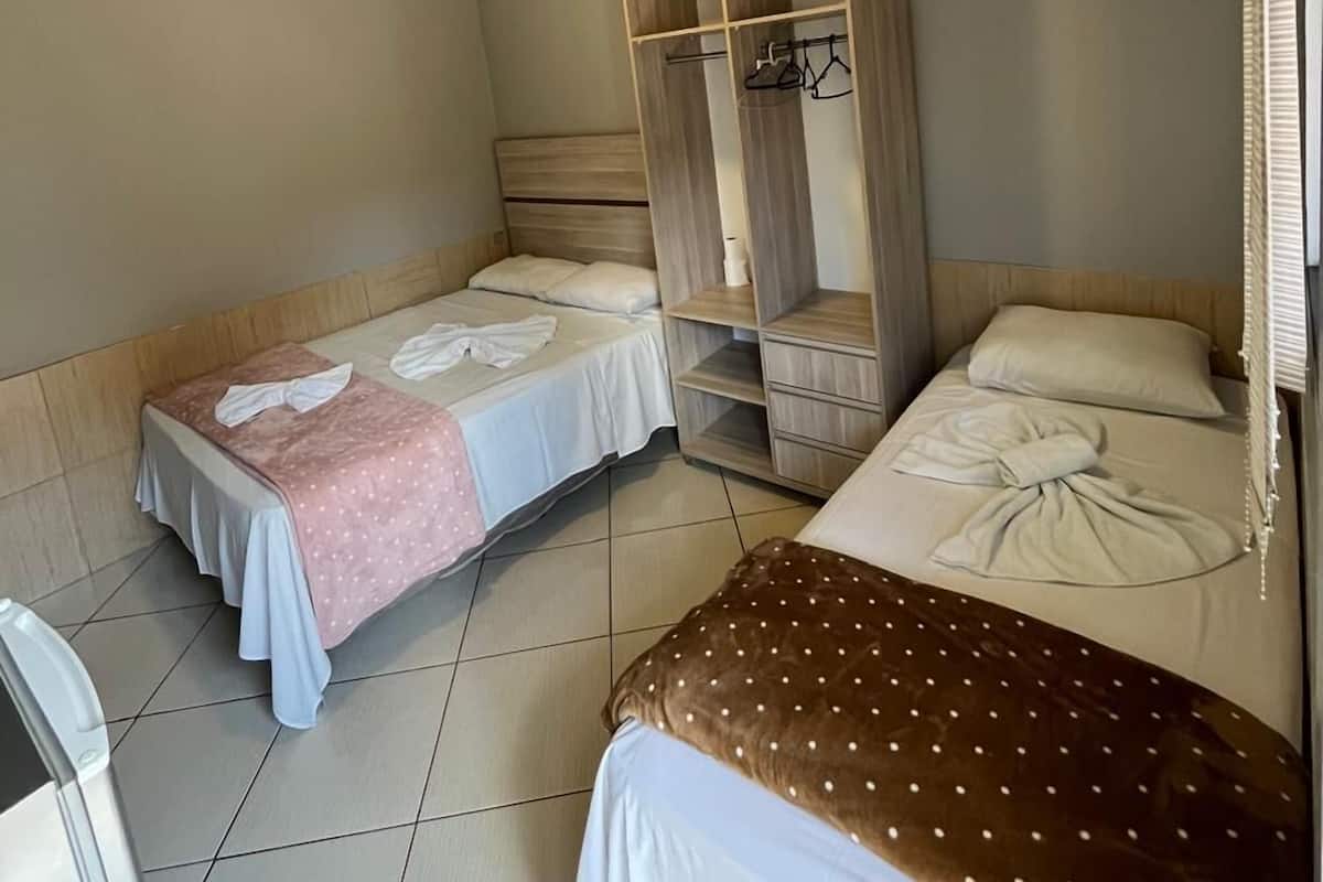 Een hotelkamer met twee bedden, een garderobe en een klein tafeltje.
