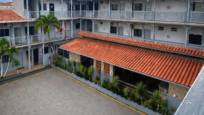 Un hotel de varios pisos con patio interior, balcones y tejado de tejas rojas.