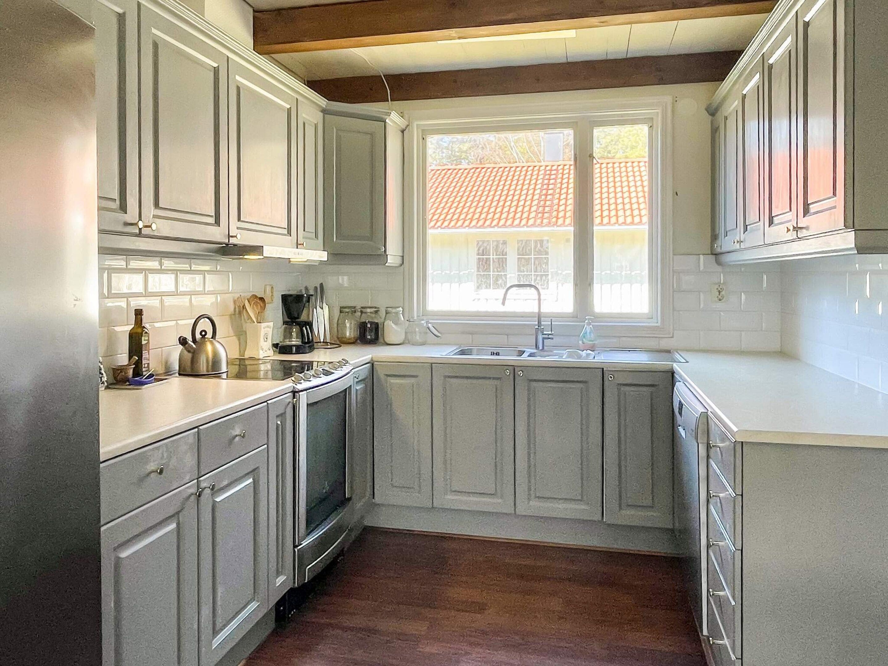 A kitchen with white cabinets, a built-in oven, and a window with a view of a red-tiled roof.