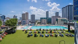 A rooftop pool area with multiple lounge chairs and a swimming pool, surrounded by high-rise buildings. - Bayview 2BR Retreat | Stunning Views + Pool (Miami)