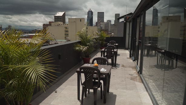 A rooftop terrace with tables and chairs, potted plants, and a city skyline view. - SAANA Living & Hotel Downtown Bogota (Bogota)