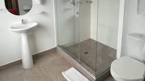 A modern bathroom with a glass-enclosed shower, a pedestal sink, and a toilet. - SAANA Living & Hotel Downtown Bogota (Bogota)