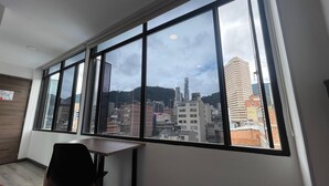 A room with a large window offering a city view, a wooden desk, and a chair. - SAANA Living & Hotel Downtown Bogota (Bogota)