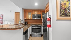 A compact kitchen with granite countertops, stainless steel appliances, and wooden cabinets. - Ocean Front Old San Juan Private Terrace (San Juan)