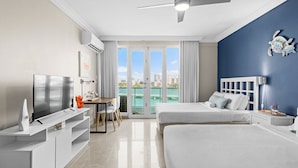 Una habitación de hotel moderna con una cama grande, televisión, escritorio y vista al mar.