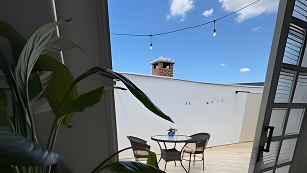 Une vue depuis un balcon, avec une plante en pot, une table et des chaises.