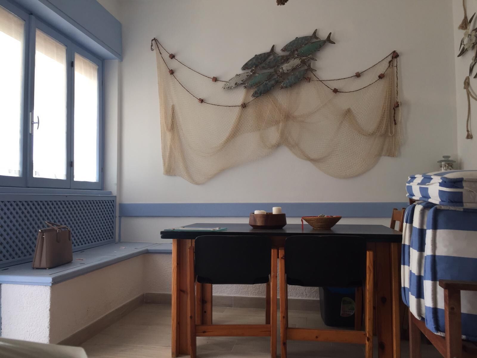 Un comedor con una mesa y sillas, una ventana con persianas y un adorno colgado en la pared.