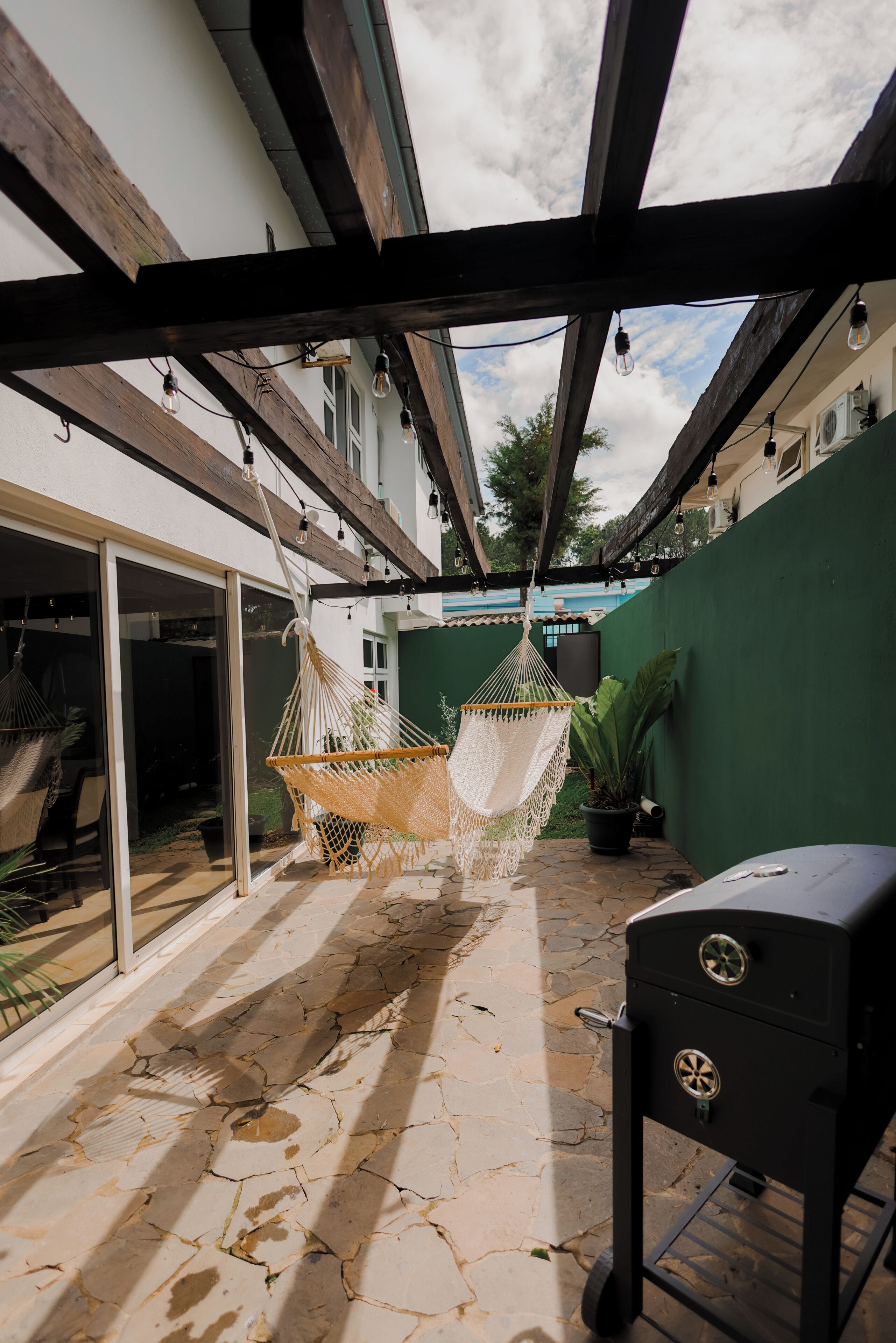 Un espace patio aménagé avec un hamac, un barbecue et un mur végétal.