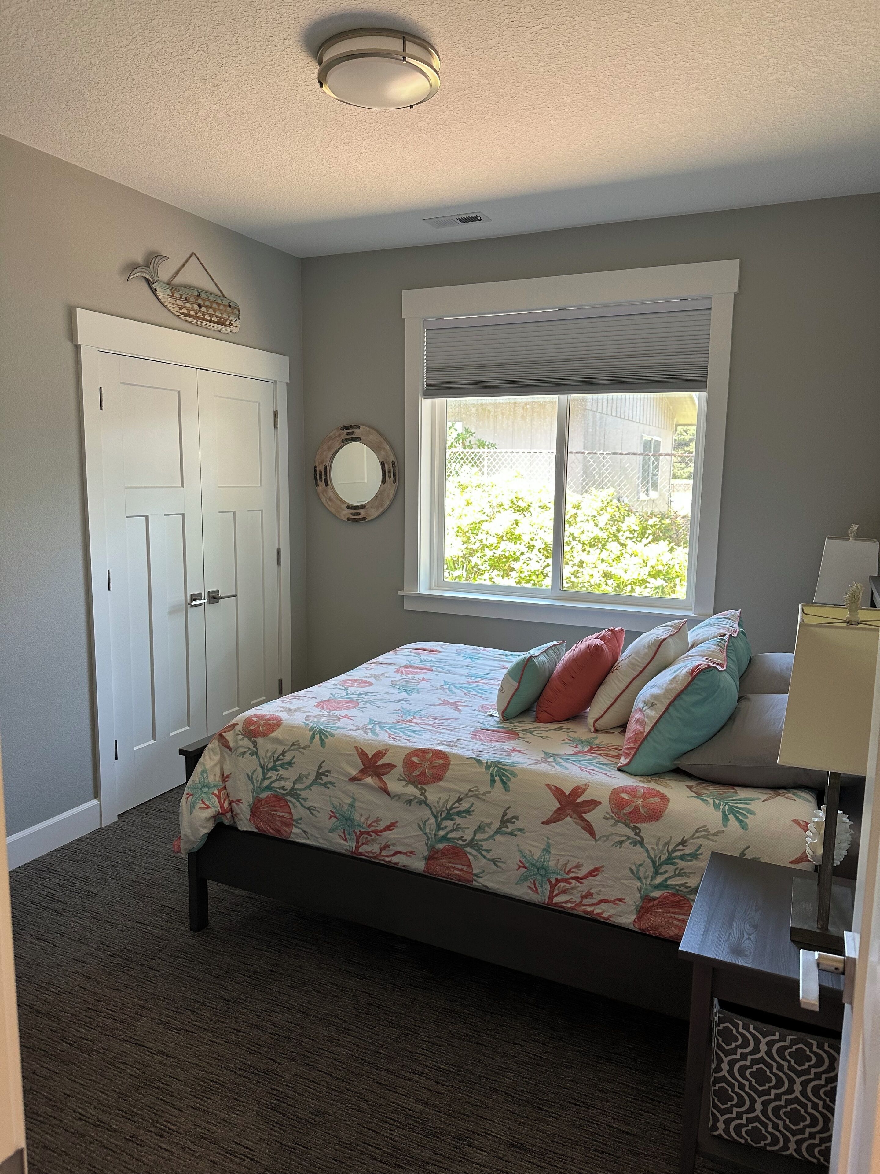 Ein Schlafzimmer mit Bett, Fenster, Tür und Deckenleuchte.