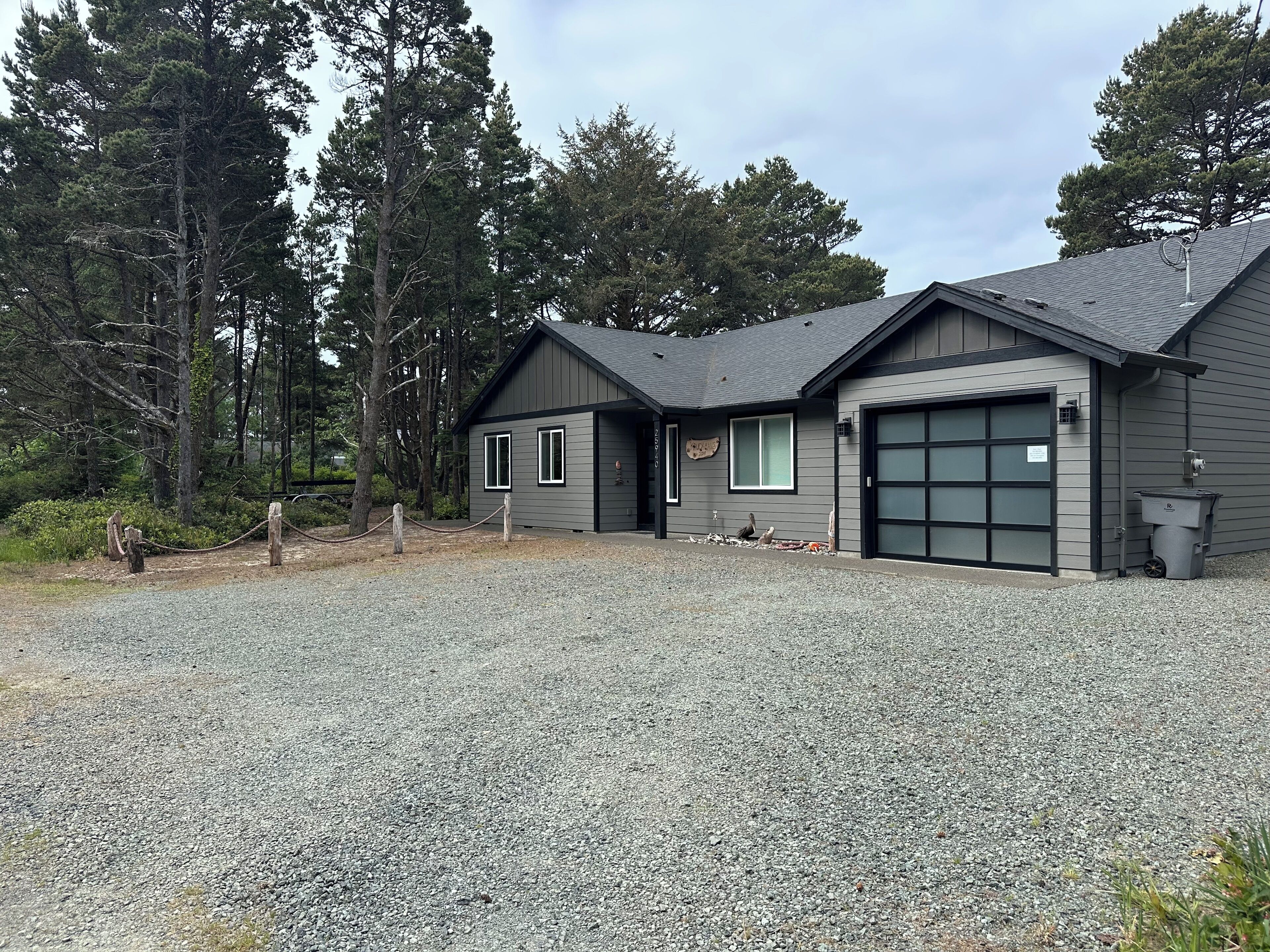 Ein modernes, zweistöckiges Haus mit Schotterauffahrt, Garage und umzäunter Garten.