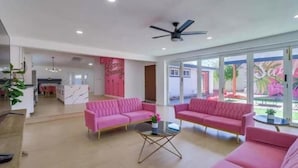 A spacious living area with pink sofas, a glass coffee table, and a ceiling fan. - Sunny Villa Lake Trails Beach (La Mesa)