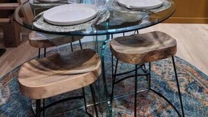 A dining area with a glass table set for four, surrounded by wooden stools. - Sunny Villa Lake Trails Beach (La Mesa)