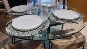 A dining area with a glass table set for four, surrounded by wooden stools. - Sunny Villa Lake Trails Beach (La Mesa)