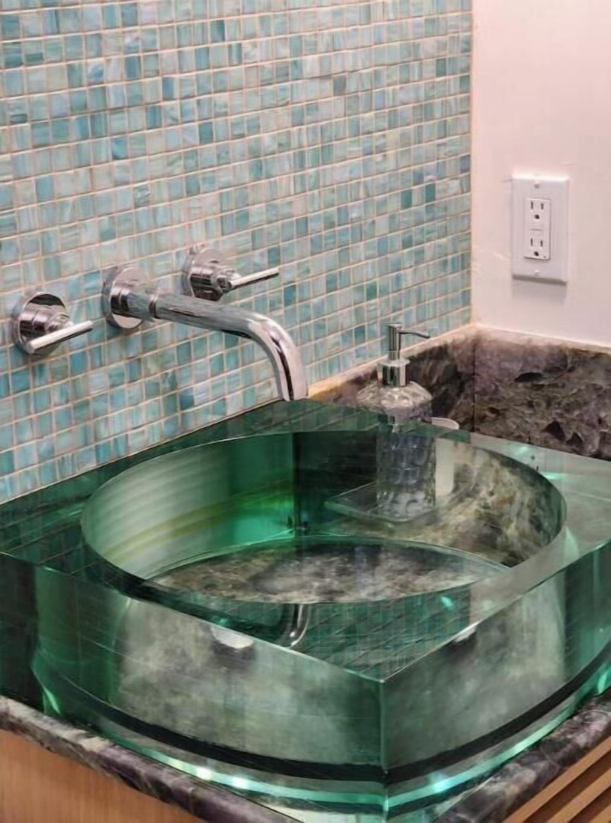 A glass bowl sink with a modern faucet, set against a tiled backsplash.