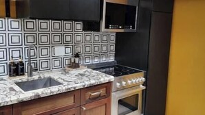 A kitchen with a marble countertop, a stove, a microwave, and wooden cabinets. - Sunny Loft Beaches Lakes Trails (La Mesa)