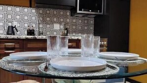 A modern kitchen with a glass dining table, wooden chairs, and a patterned backsplash. - Sunny Loft Beaches Lakes Trails (La Mesa)