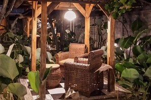 A covered outdoor seating area with wicker furniture and potted plants. - Sanur Lodge (Bali)