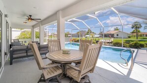 Un espace extérieur abrité comprenant une piscine, une table avec des chaises et un canapé.