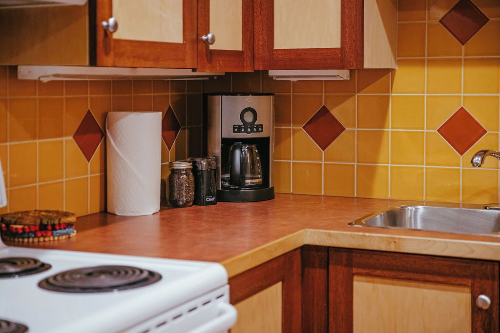 A kitchen with wooden cabinets, a coffee maker, and a stove.