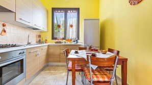 A kitchen with wooden cabinets, a stove, and a dining table with chairs.